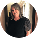 Circular portrait of a smiling maker with shoulder-length gray-blond hair in a black polka-dot-sleeve top