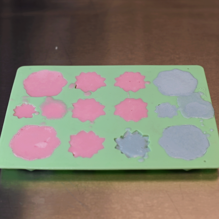 Green silicone succulent mold with cavities filled with pink and gray-blue soap