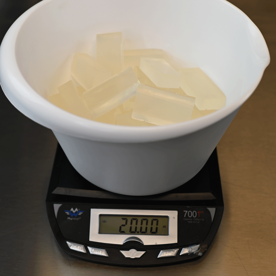 White bowl of clear soap base chunks on a digital scale reading 200 grams