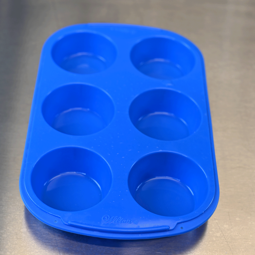 Empty blue six-cavity silicone muffin mold on a stainless steel counter