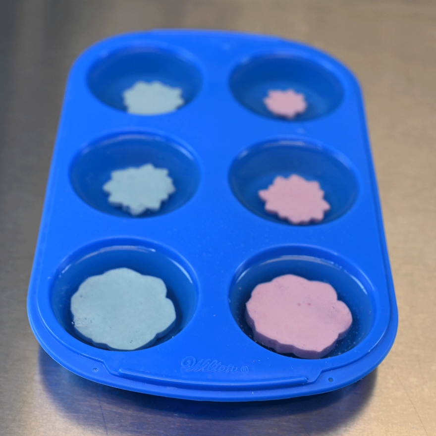 Blue silicone muffin mold with a blue or pink succulent soap embed in each cavity
