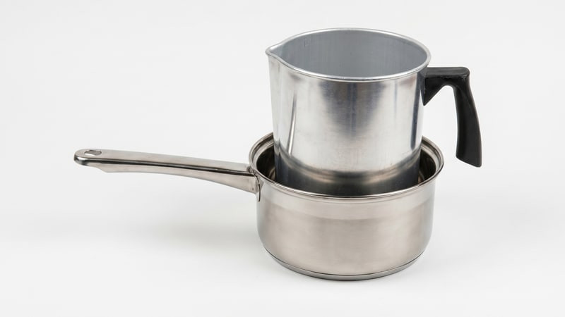 Aluminum pouring pitcher set inside a stainless saucepan as a double boiler