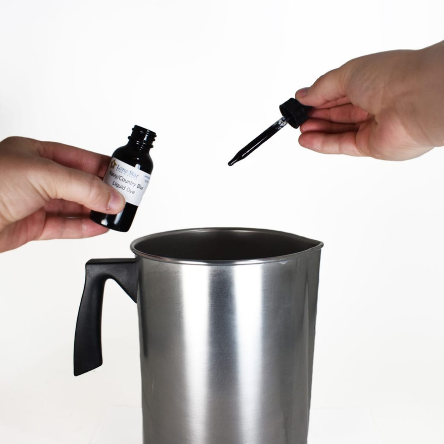 Hands holding a Lone Star Navy/Country Blue liquid dye bottle and dropper over a pouring pitcher